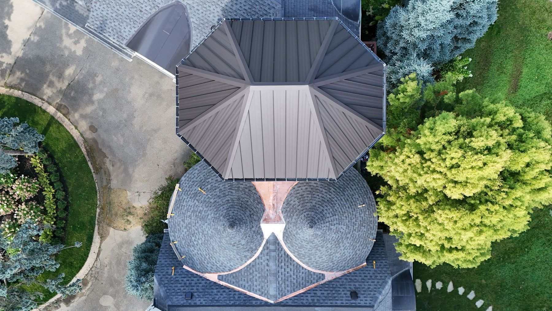 Overhead view of a gray-roofed building surrounded by trees and a curved walkway