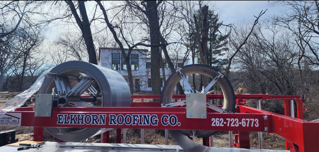 Red truck carrying giant metal hose coils in a snowy yard; sign reads “C. Clark Fencing Co.”