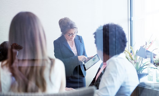 Businesswoman presenting tablet to two colleagues in modern office.
