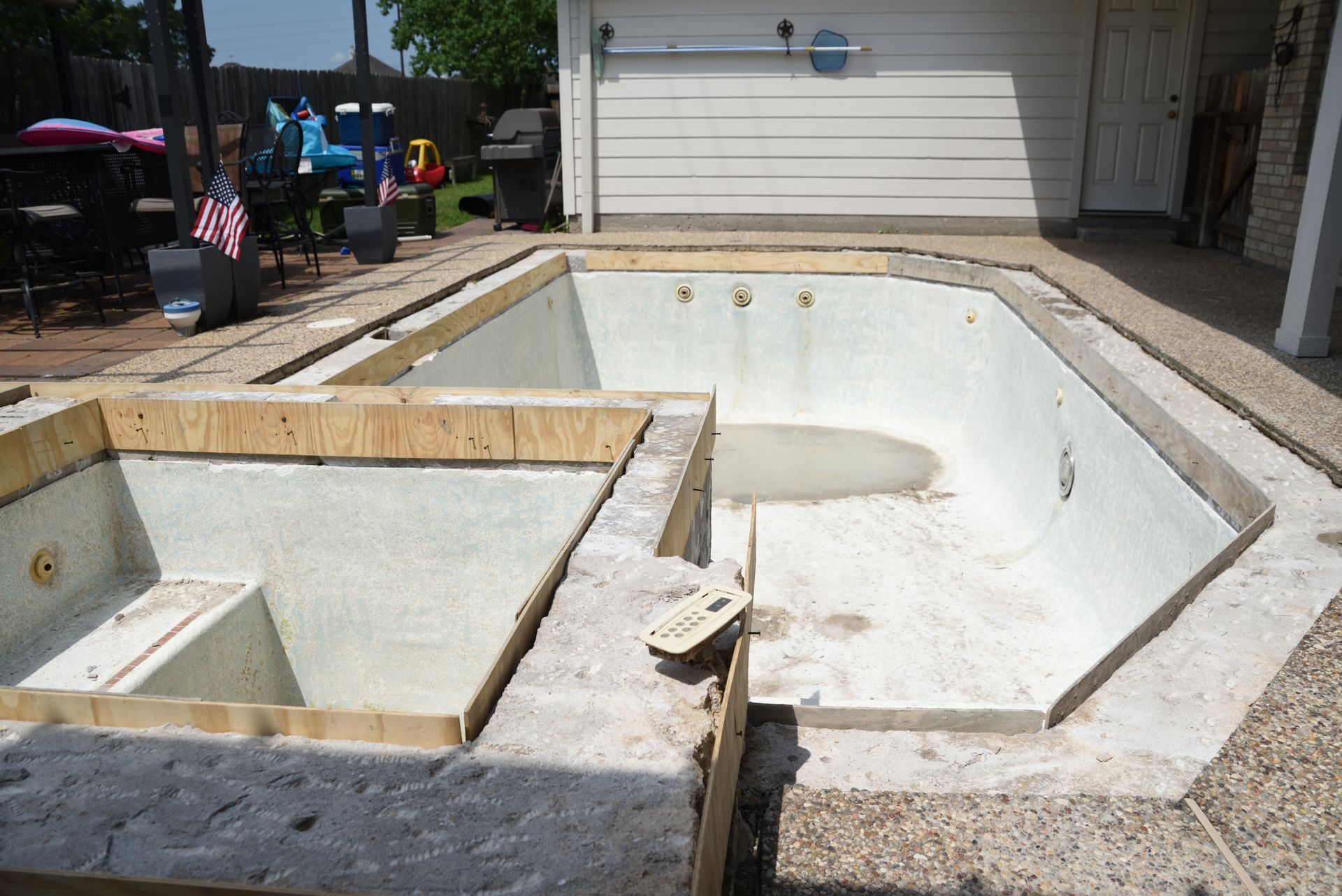 Empty pool with raised spa, under construction outdoors.