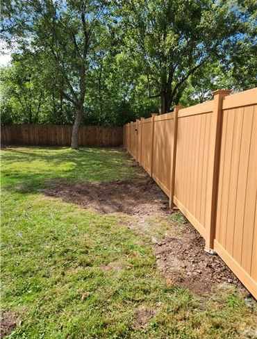 Newly installed wood-grain vinyl privacy fence