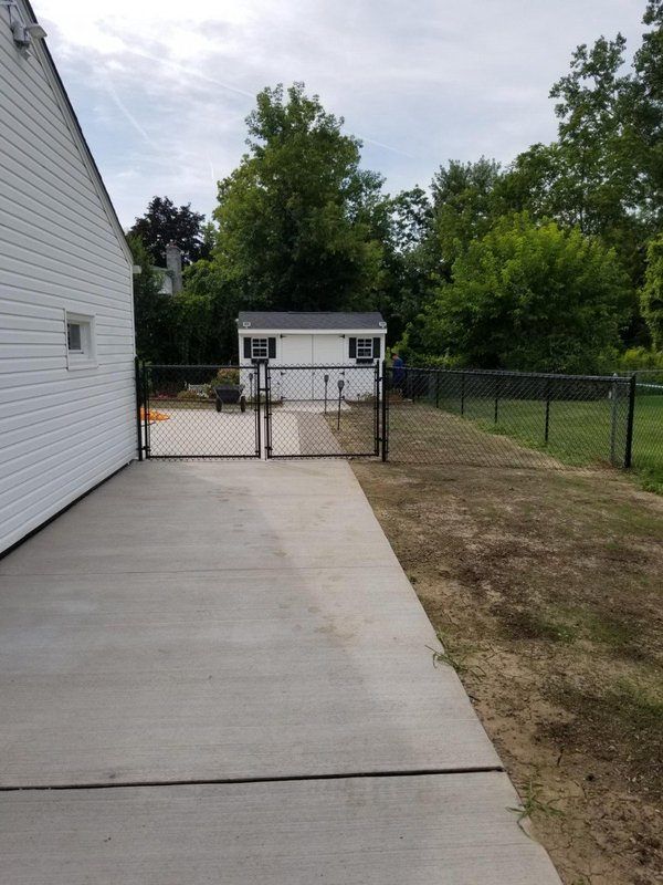Backyard with a newly installed black chain-link fence and gates