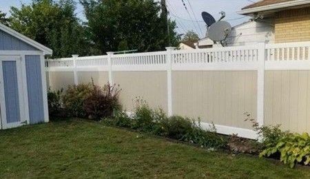 Tall white vinyl privacy fence behind a landscaped backyard garden. Tall white vinyl privacy fence behind a landscaped backyard garden.