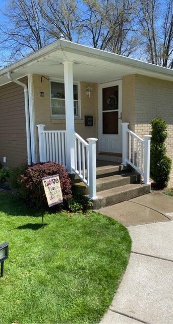 A house entrance with a covered porch and white vinyl fence