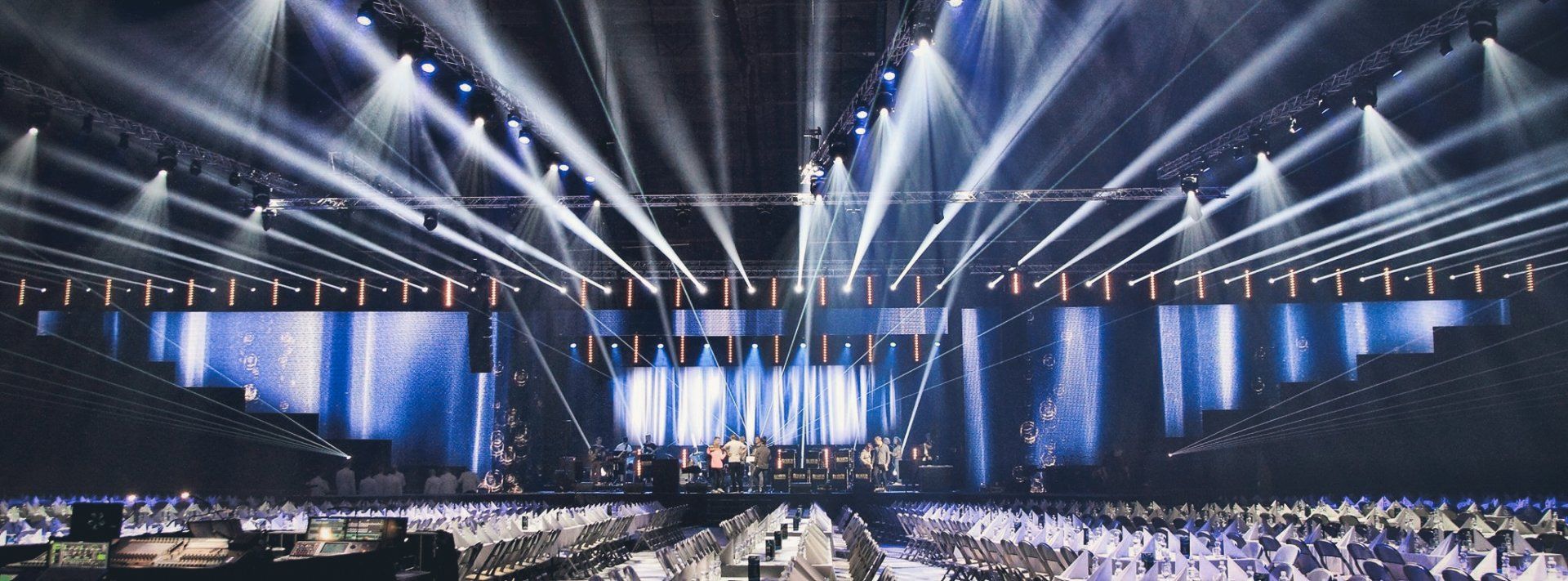 Kirkkaiden valojen valaistu konserttipaikka. Keskellä lava, jossa on bändi, ja yleisö etualalla.