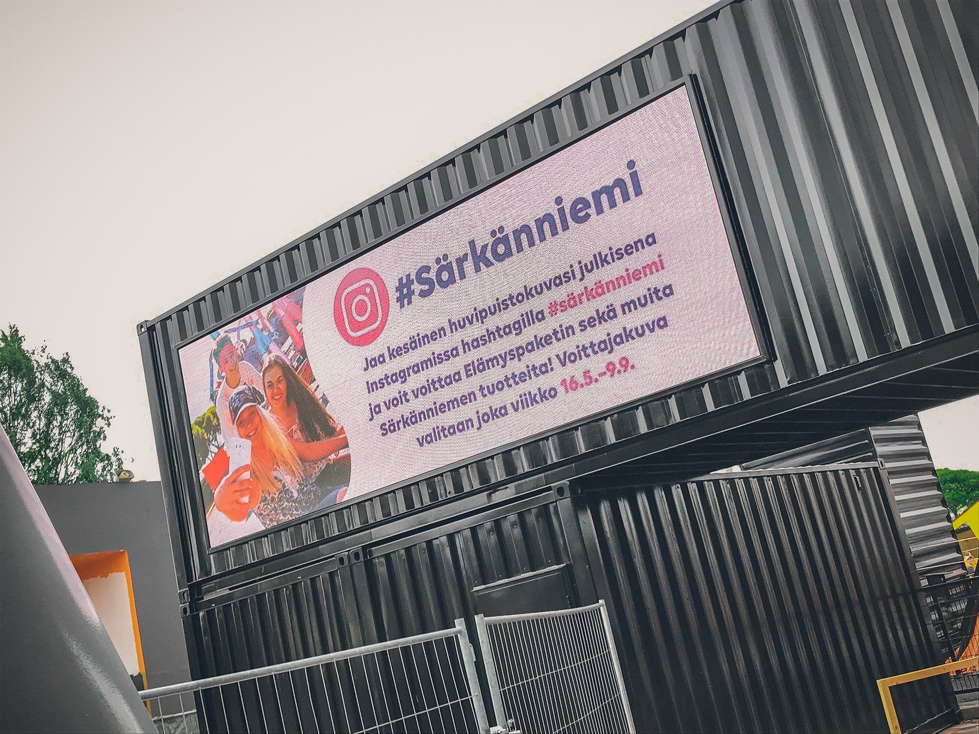 Digitaalinen näyttö mustalla merikontilla, jossa on hashtag #Särkänniemi ja Instagram-logo.