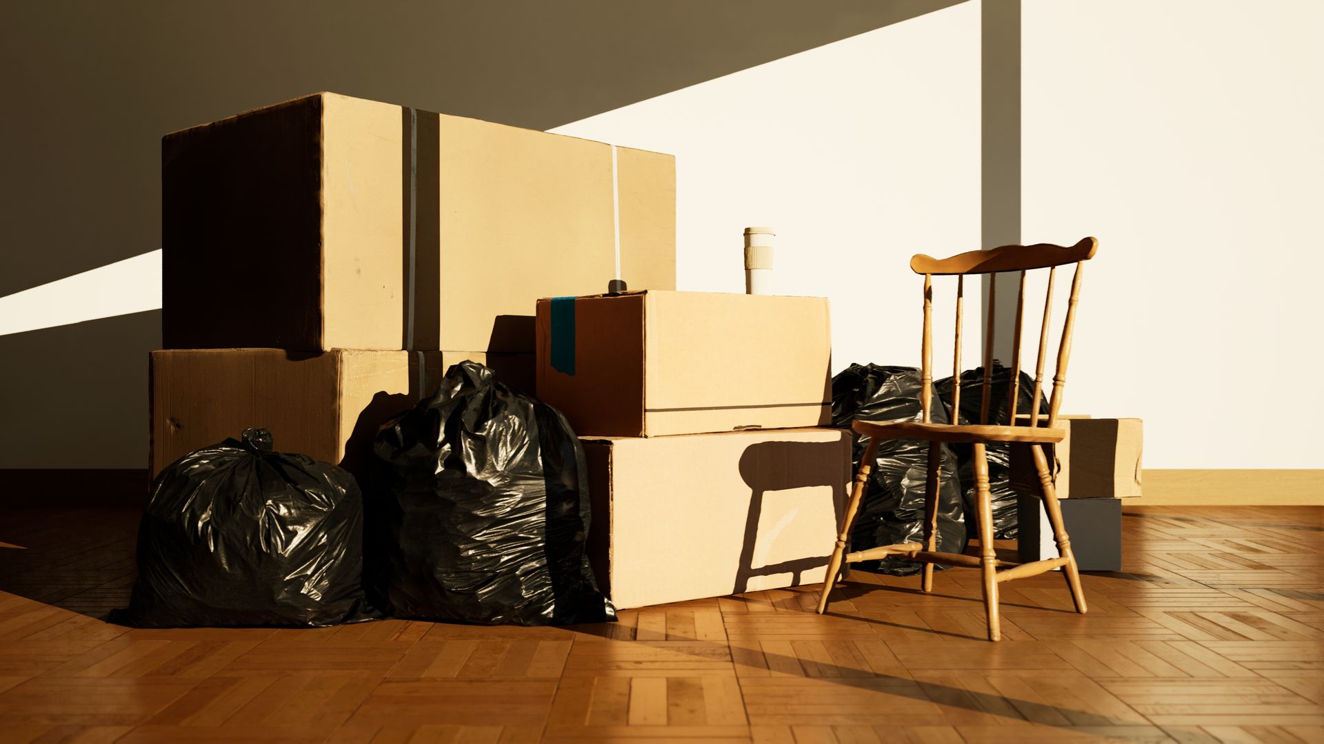 A chair is sitting next to a pile of cardboard boxes and trash bags.