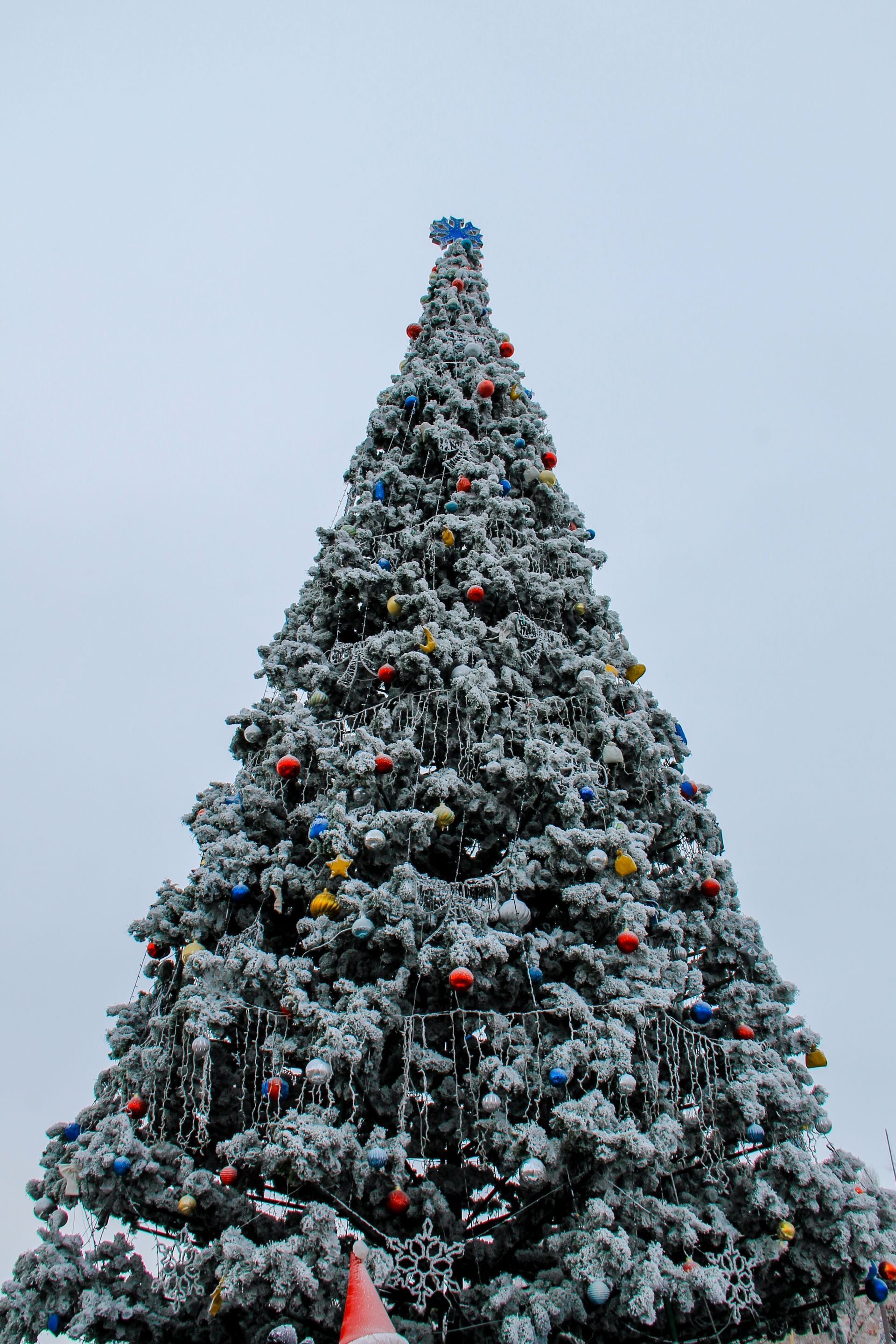 A large christmas tree is covered in snow and decorations