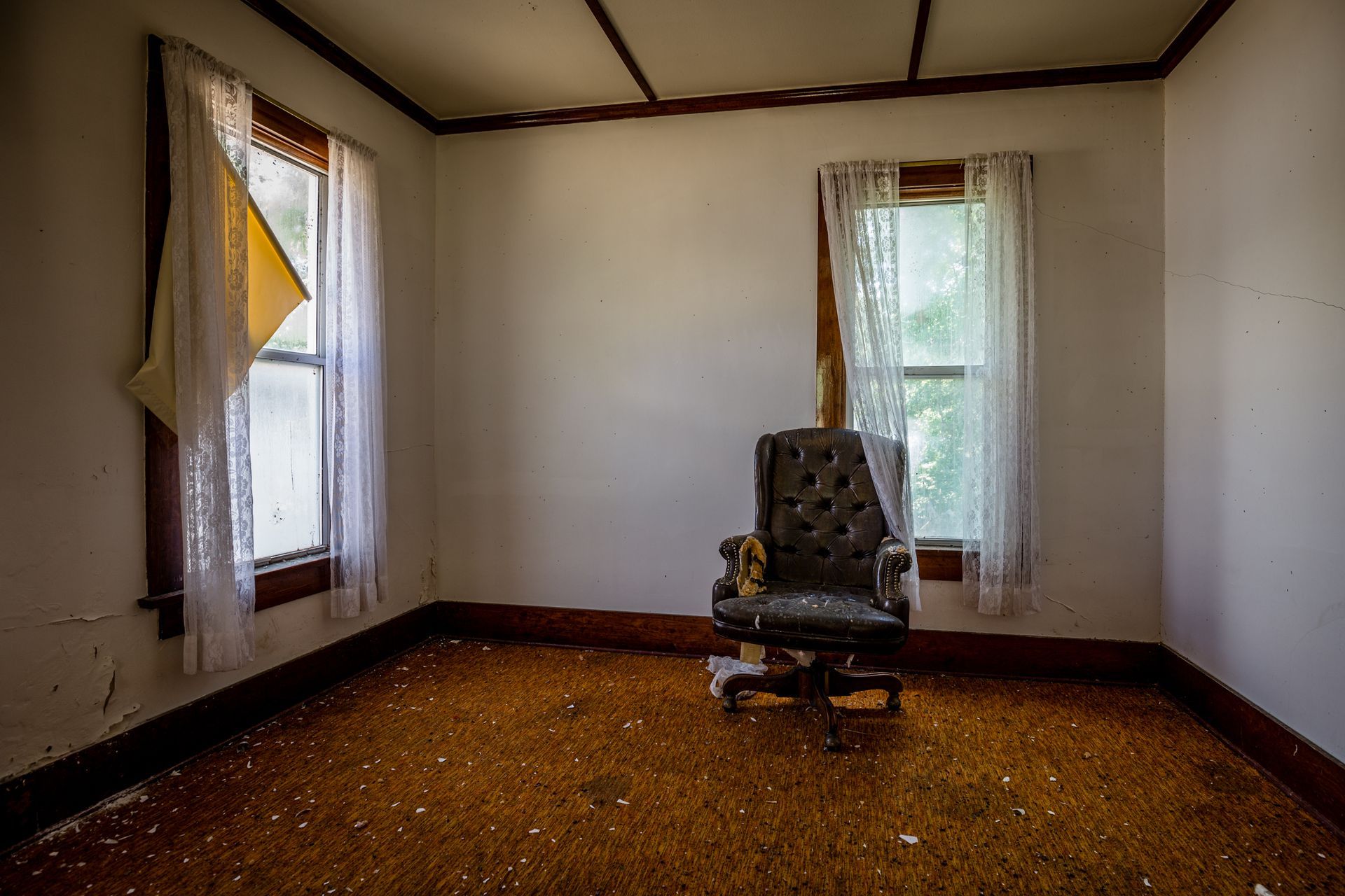 An empty room with a rocking chair and a window.