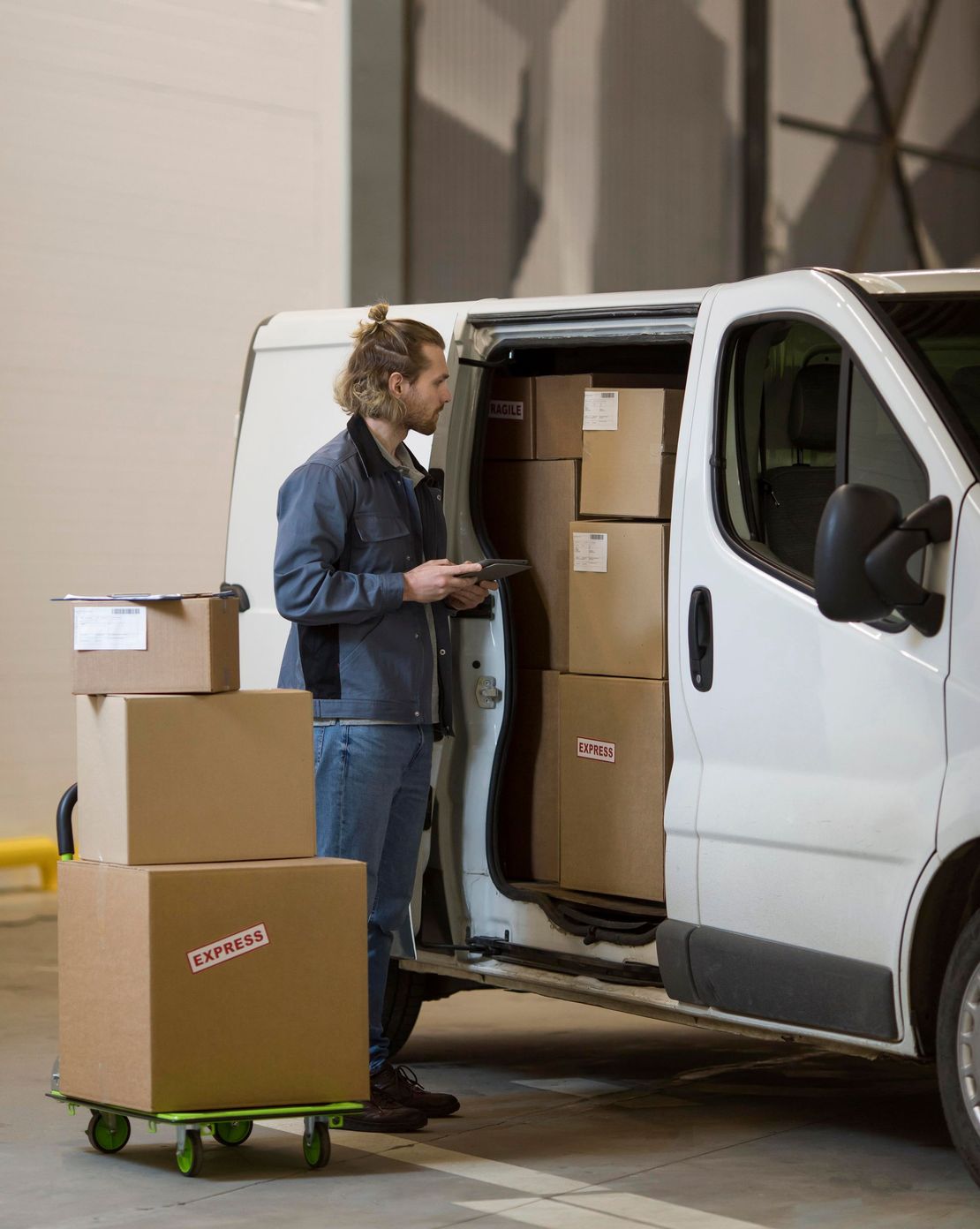 A man is loading boxes into a van in a warehouse.