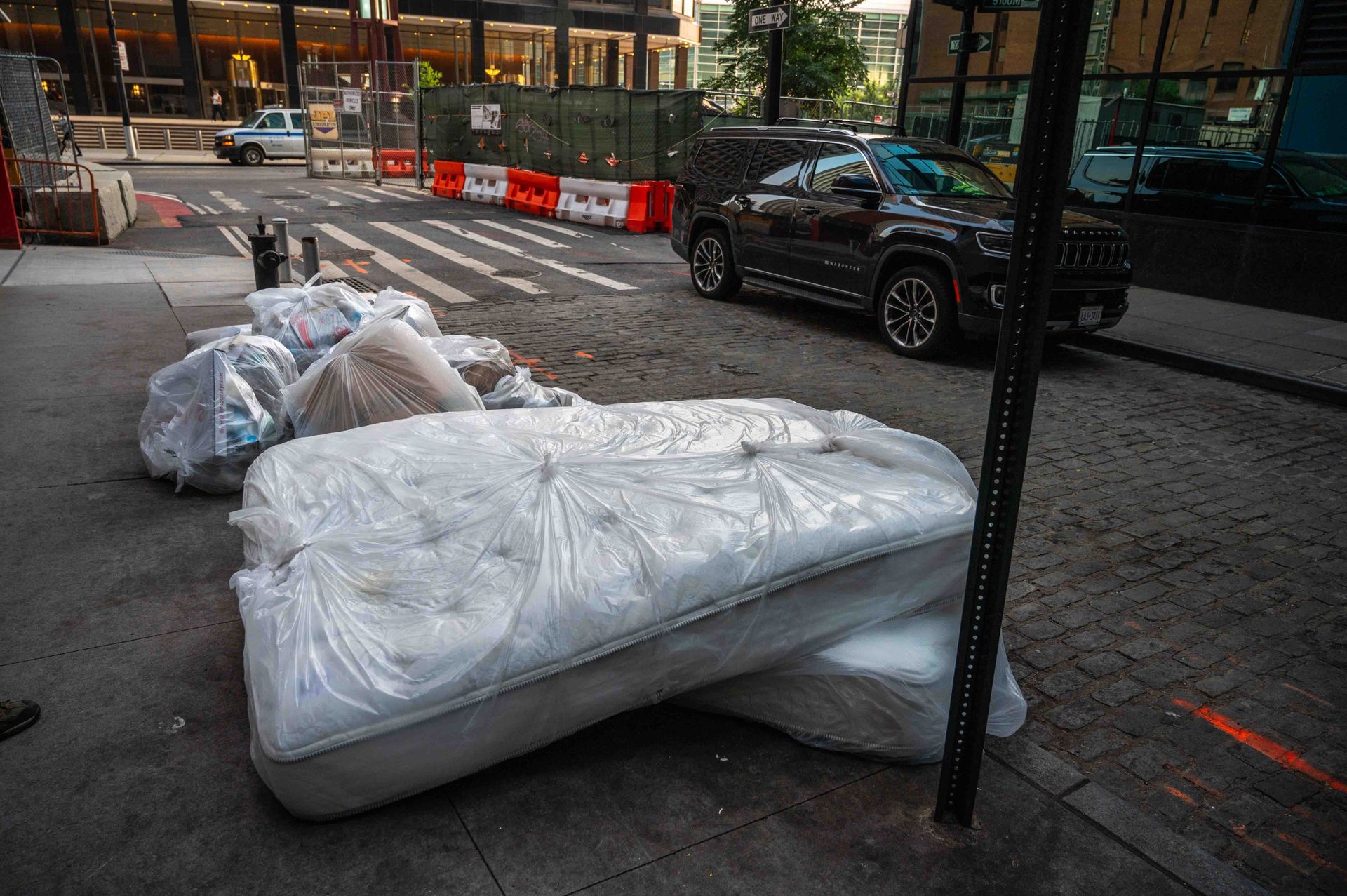 A pile of mattresses are sitting on the side of the road.