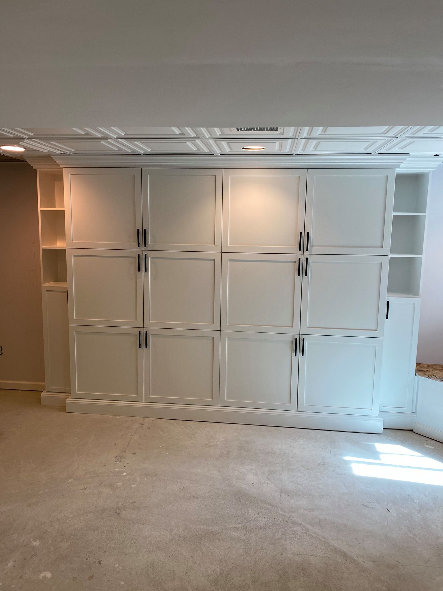 A room with a lot of white cabinets and shelves