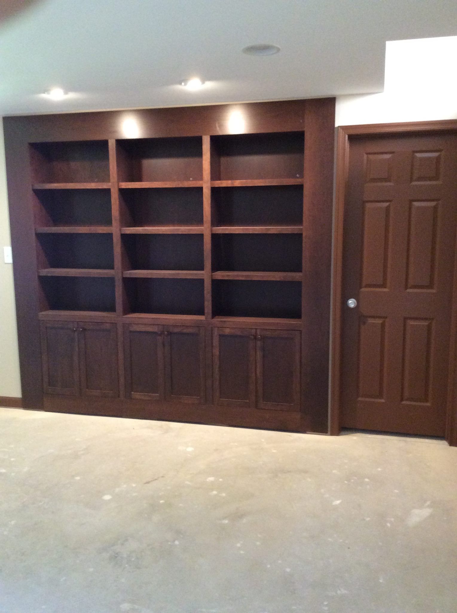 An empty room with wooden shelves and a door
