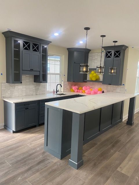 Modern kitchen with dark cabinets, white countertops, island, and pendant lights