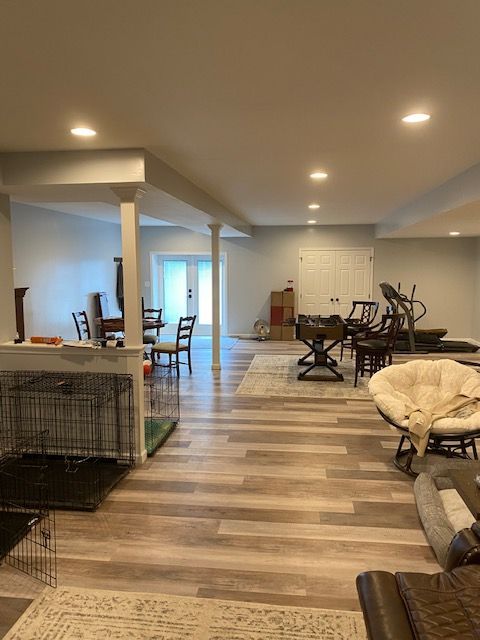 Finished basement with wood flooring, recessed lights, exercise equipment, chairs, and pet crates.