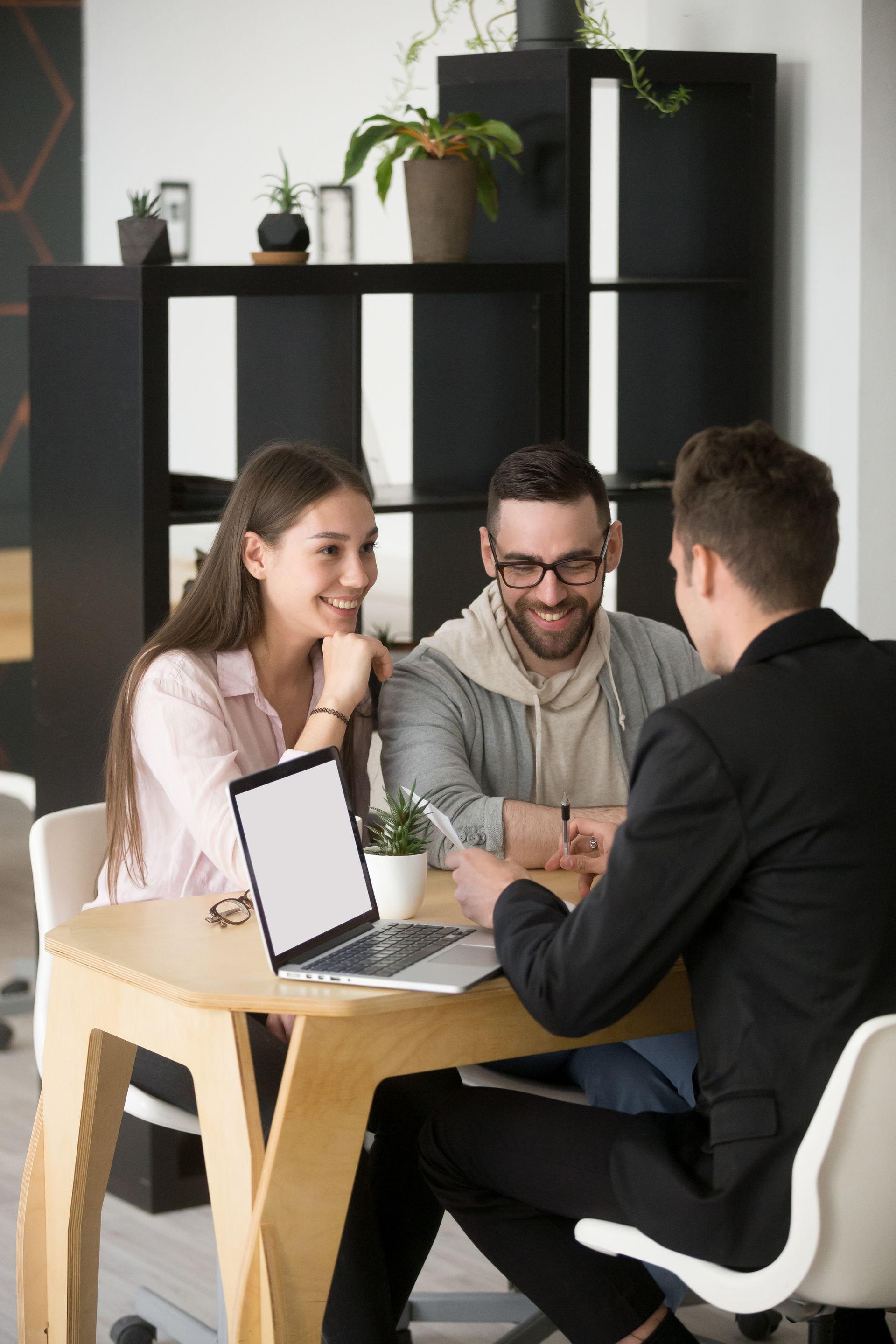 A man and a woman are sitting at a table with a laptop.