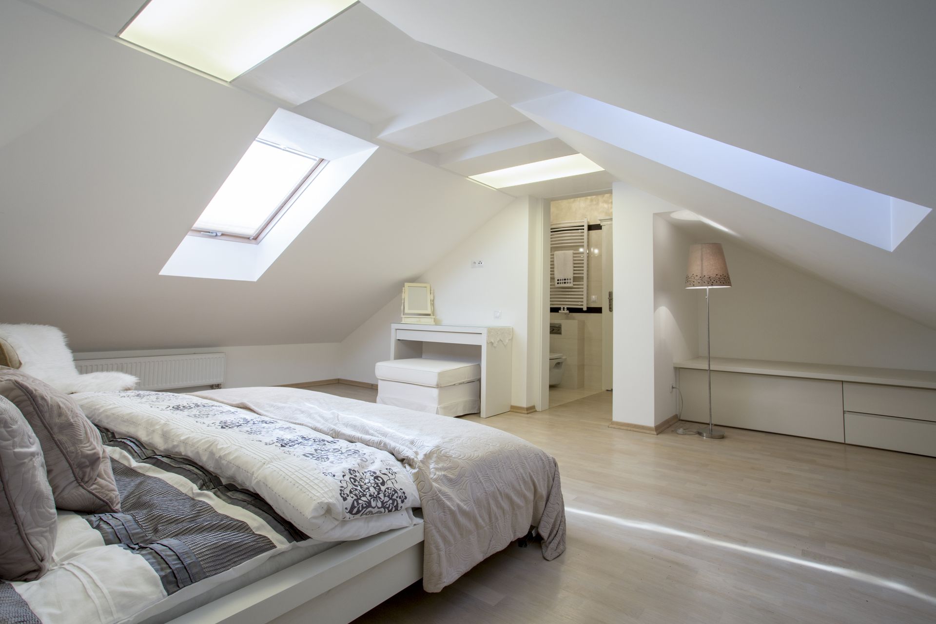A bedroom in an attic with a bed and a skylight.