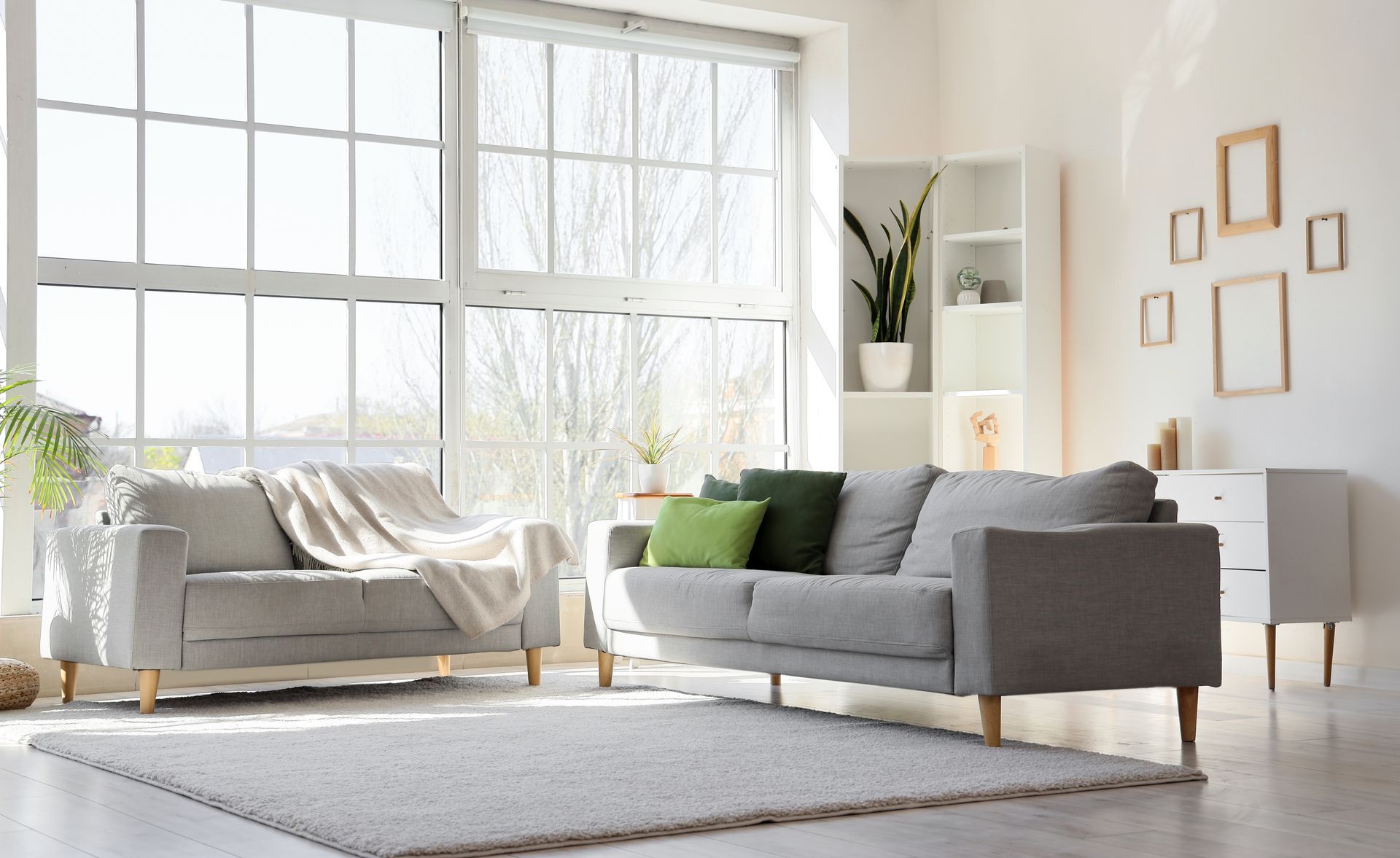 A living room with two couches , a rug , and a large window.