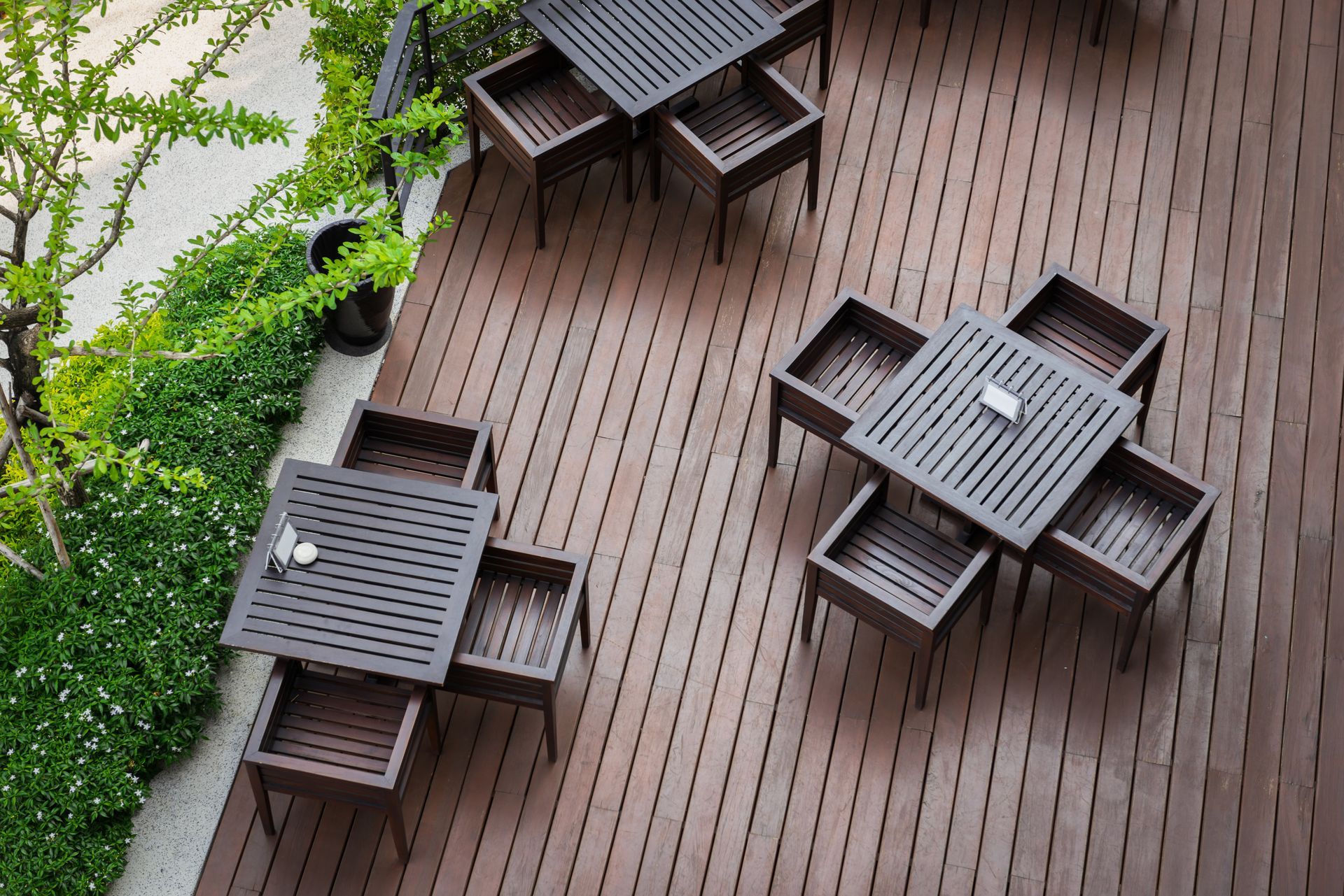 A wooden deck with tables and chairs on it.