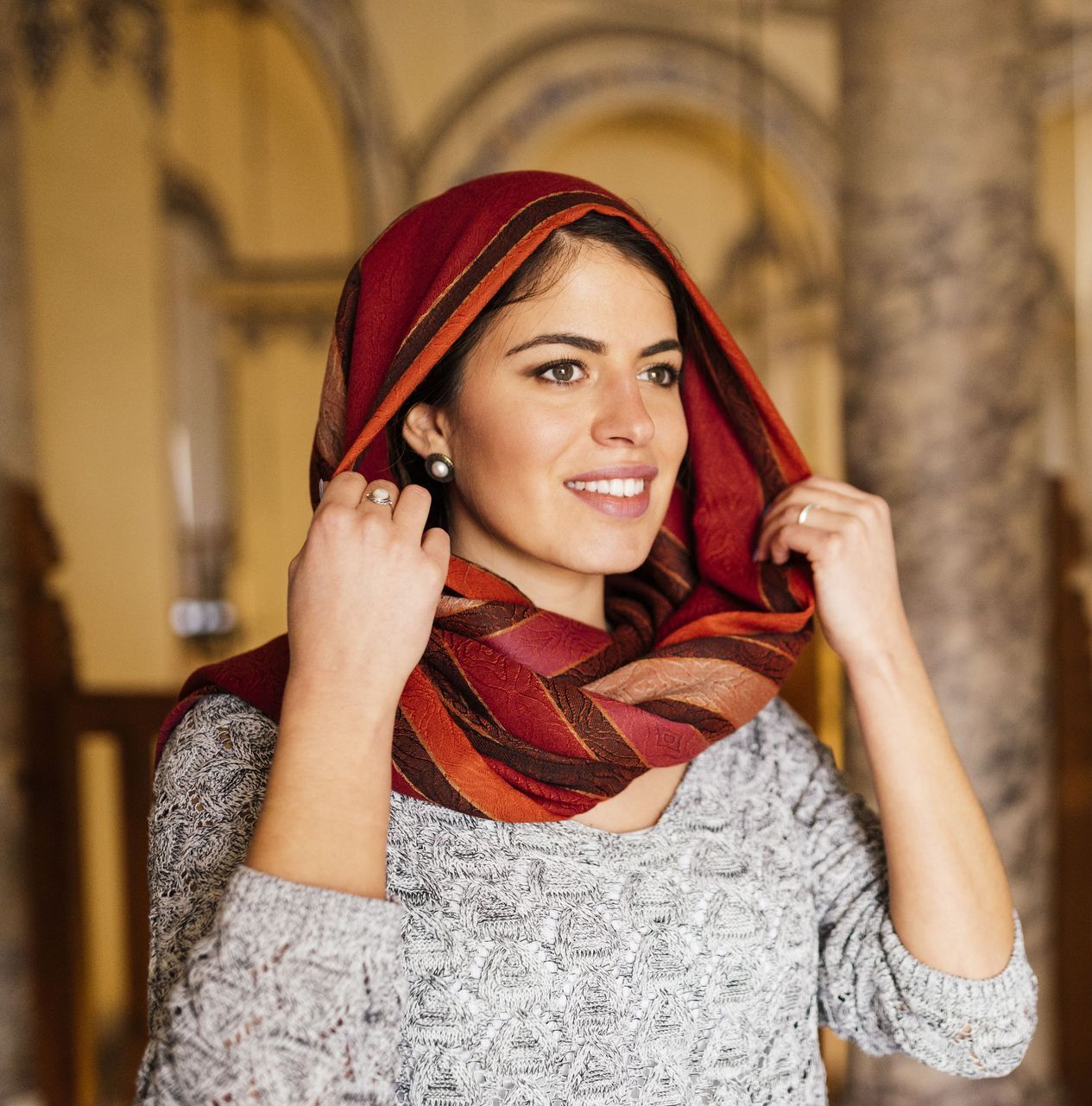 A woman wearing a scarf around her head is smiling