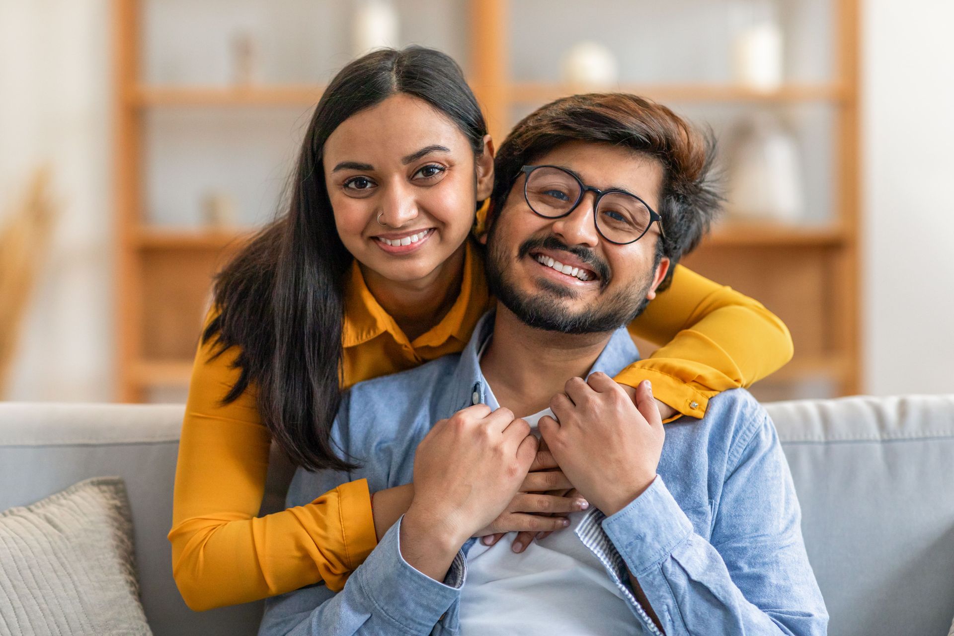 A man and a woman are posing for a picture while sitting on a couch.