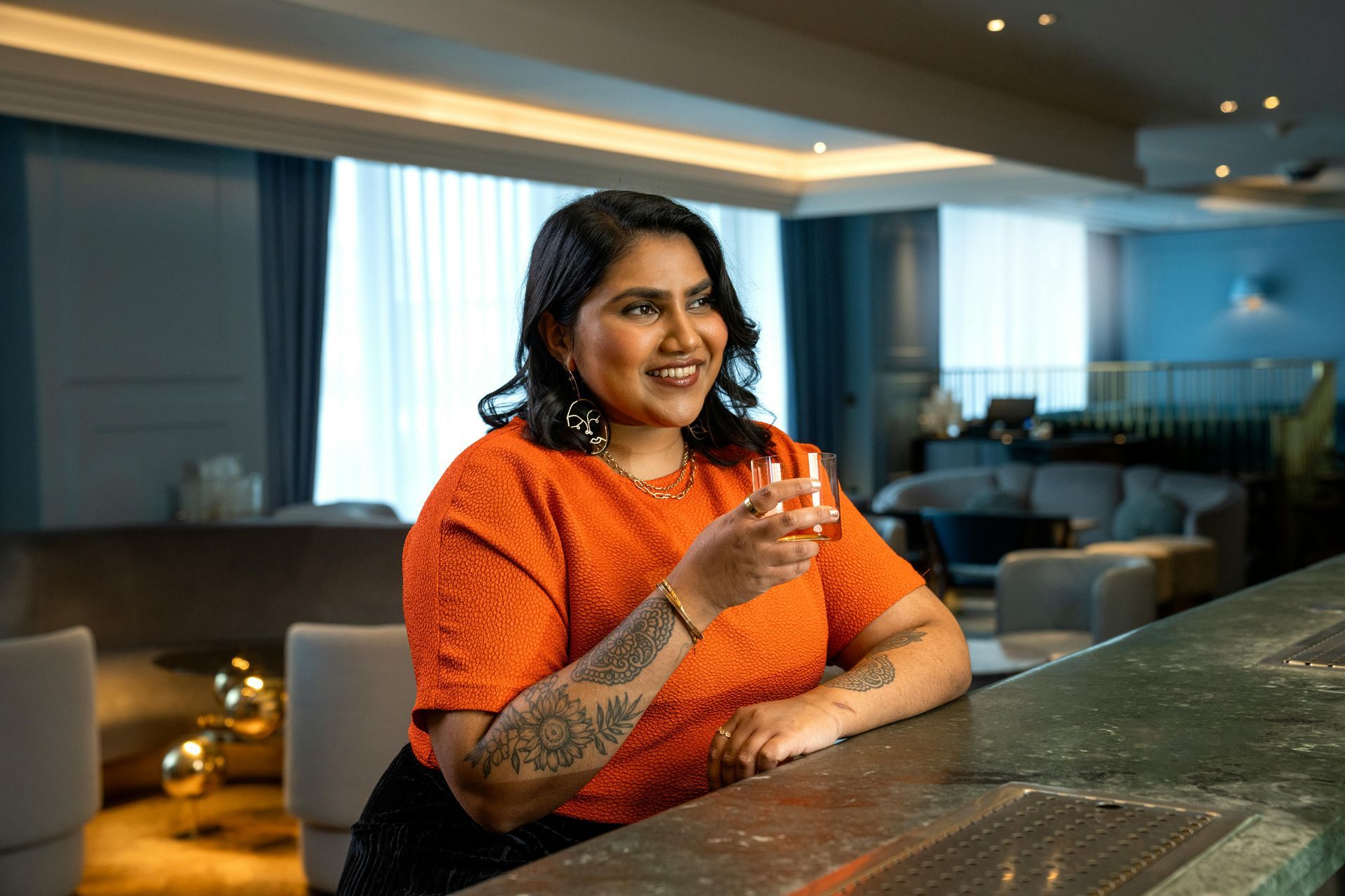 A woman is sitting at a bar holding a glass of wine.