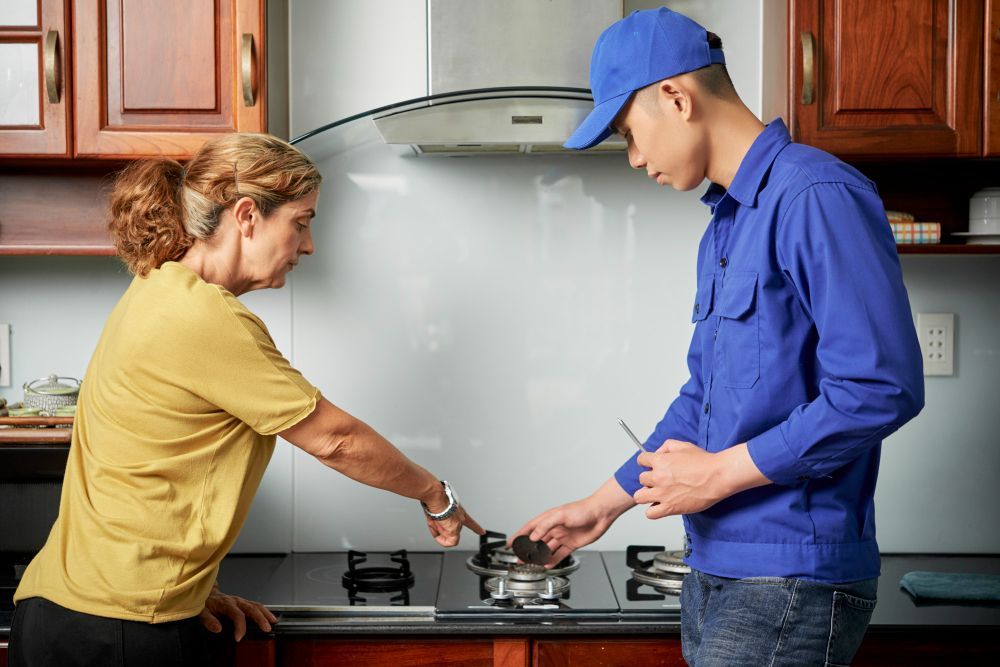 Two people cooking at a stovetop in a kitchen, stirring a pot together.