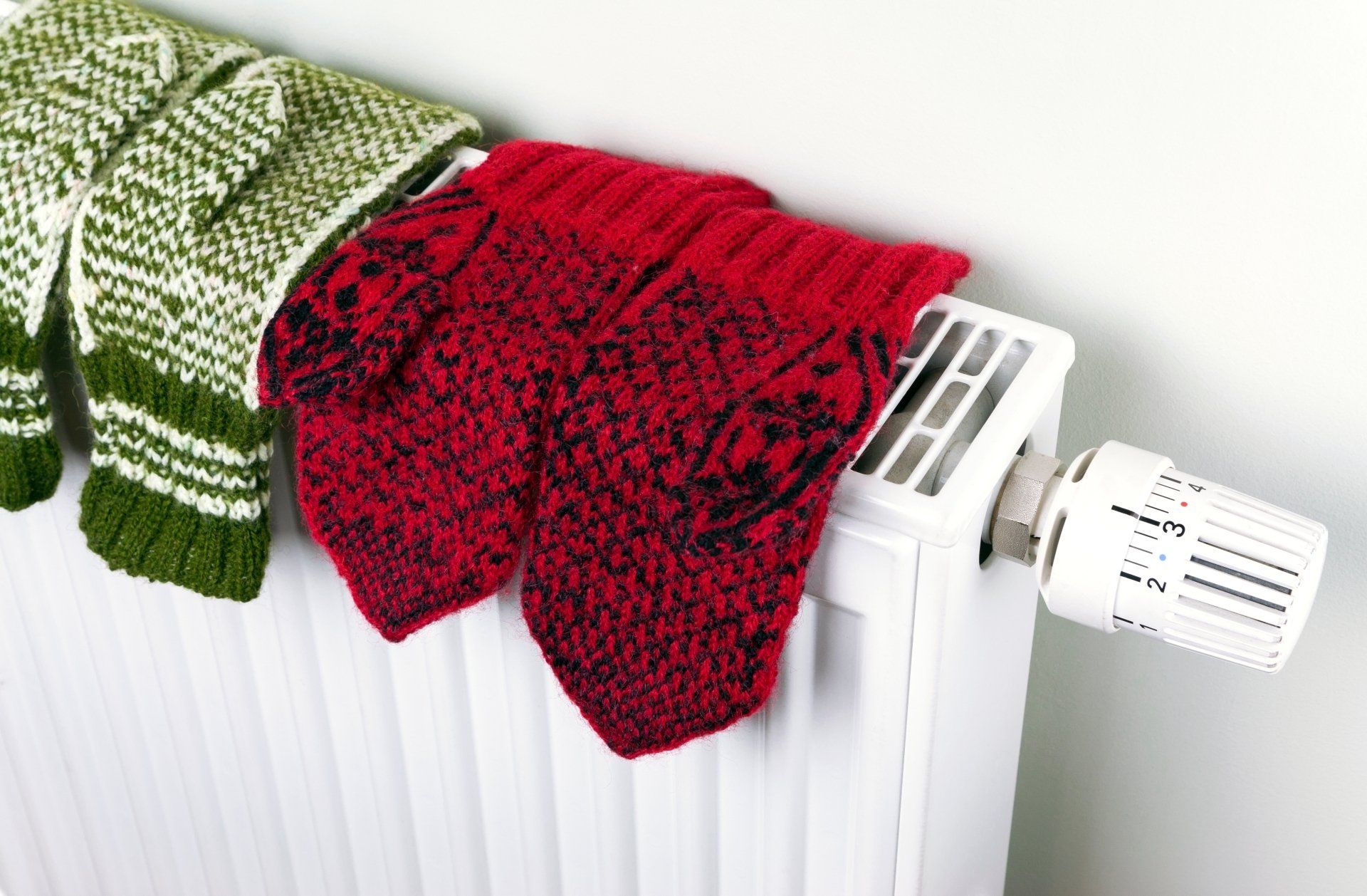 A red and green scarf is hanging on a radiator.