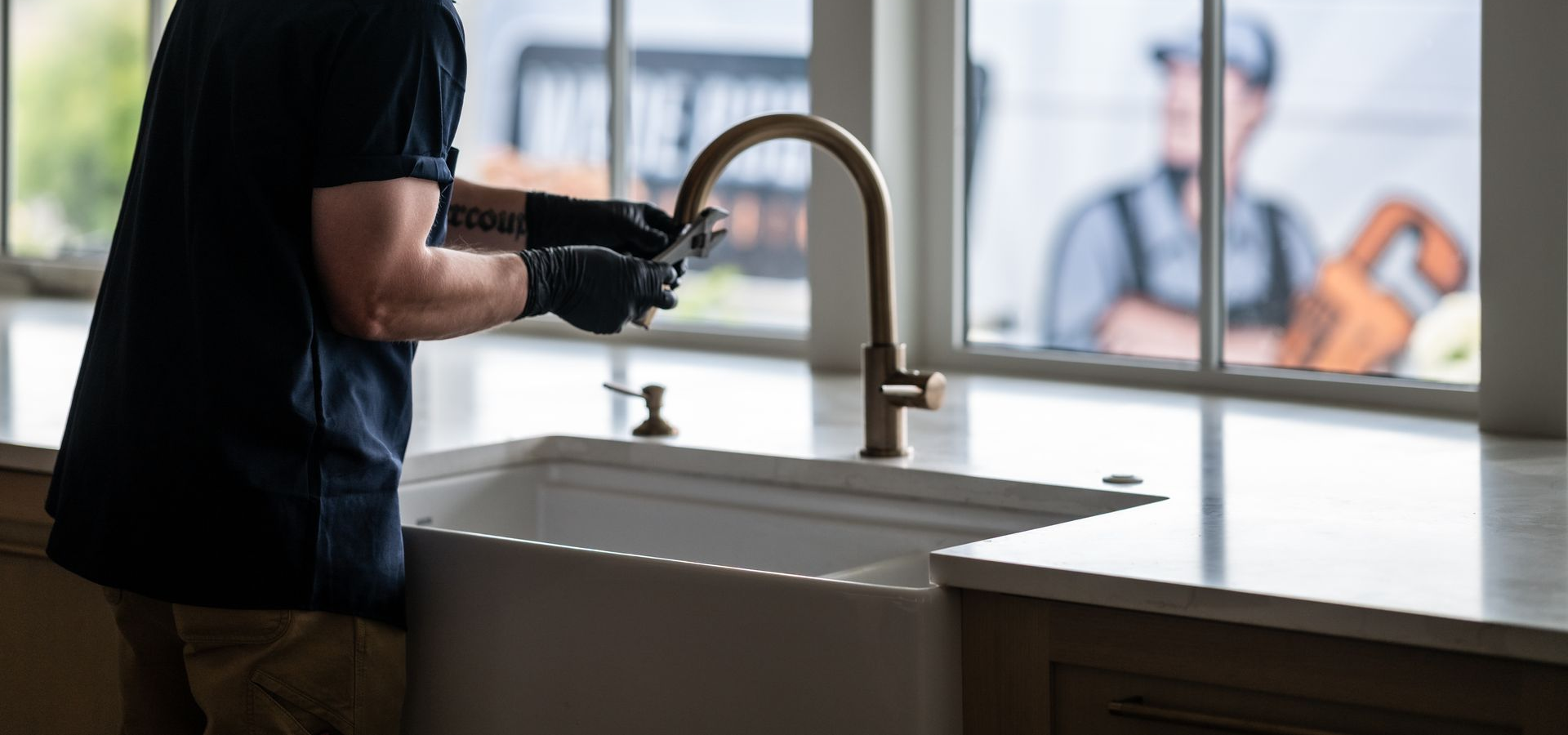 A plumber is fixing a sink in a kitchen.