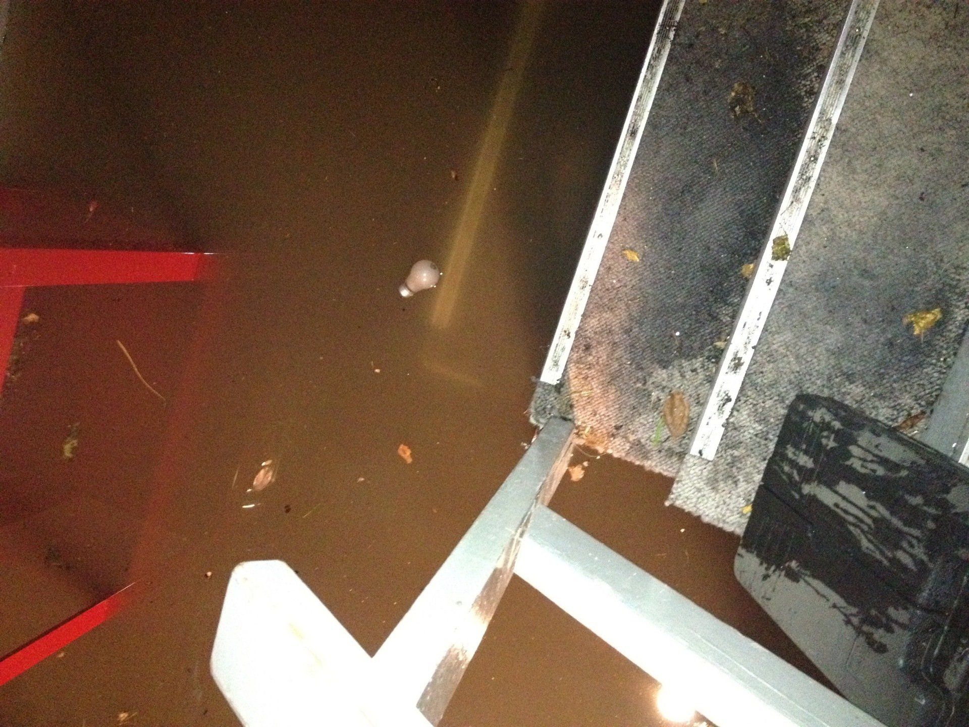 A flooded room with a red chair and a white chair