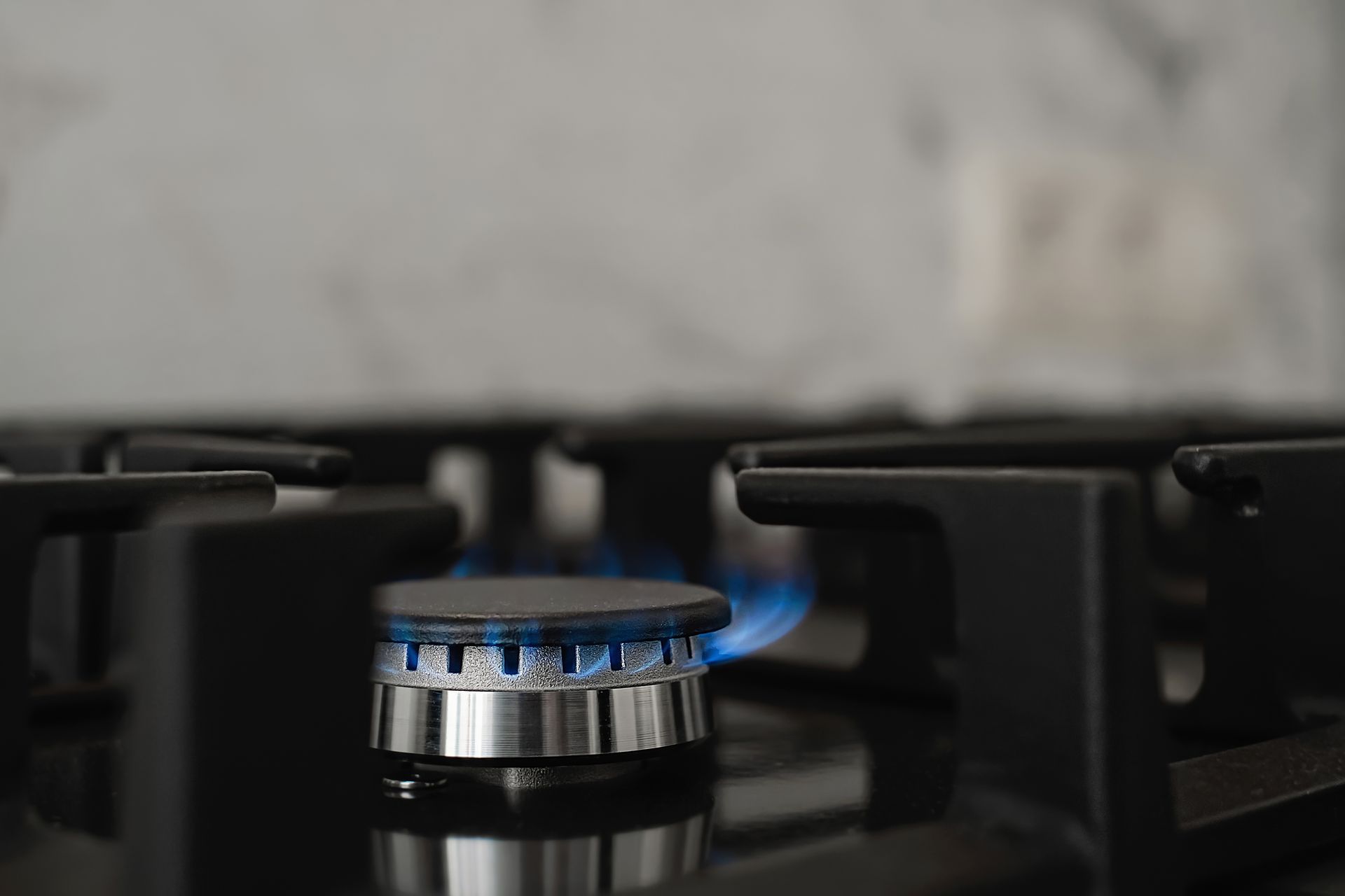 A close up of a gas stove with a blue flame coming out of it.