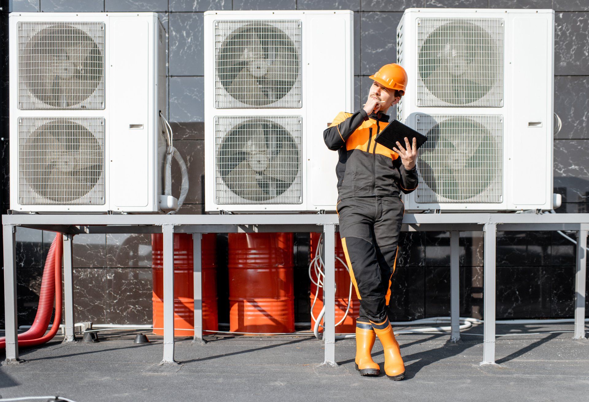 A man is standing in front of a row of air conditioners.
