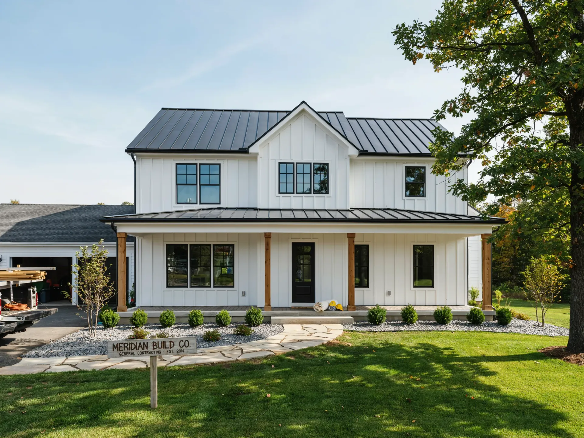 Two-story white house with black roof and front porch, set on a green lawn with trees.