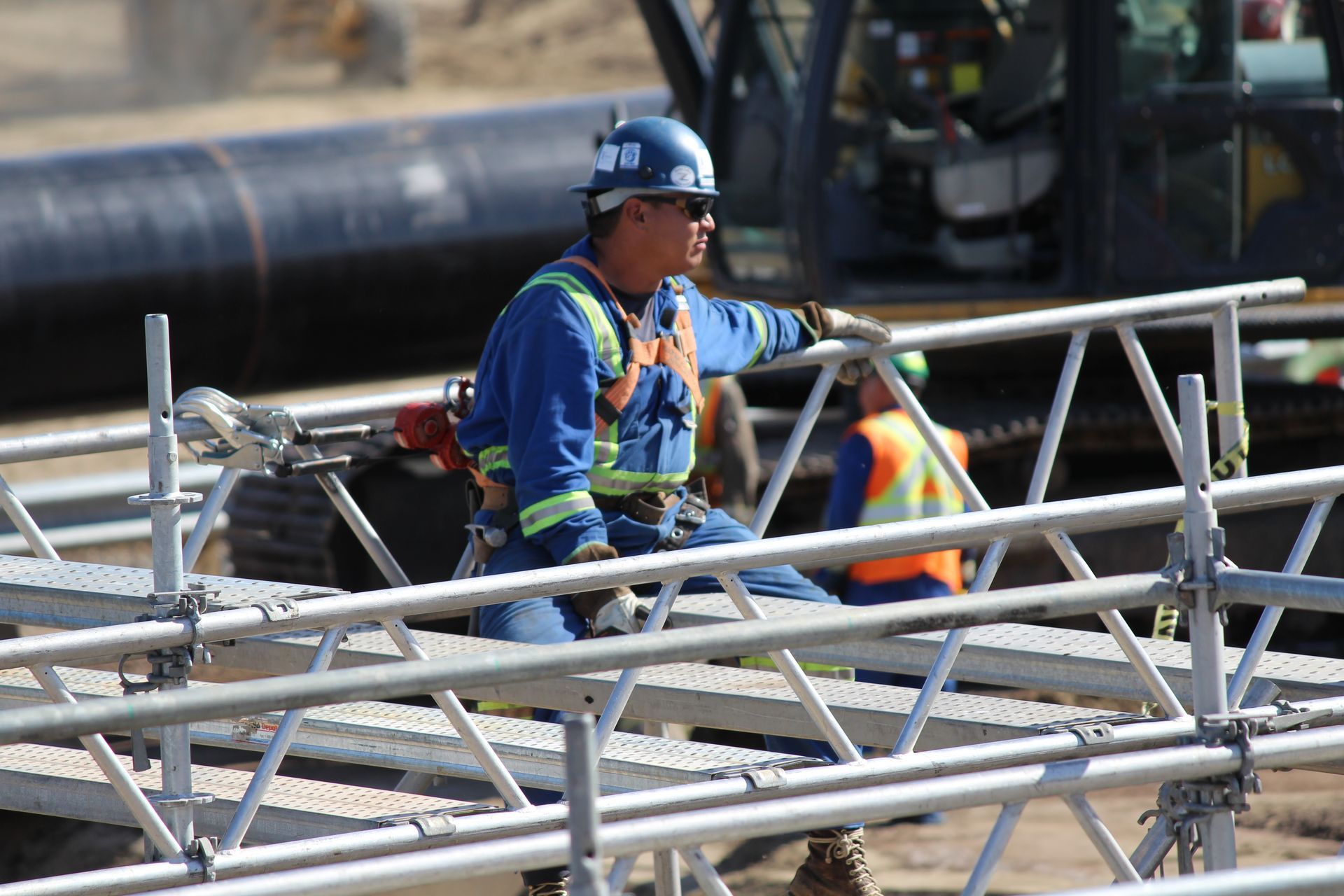Worker in blue safety gear on scaffolding at an industrial site