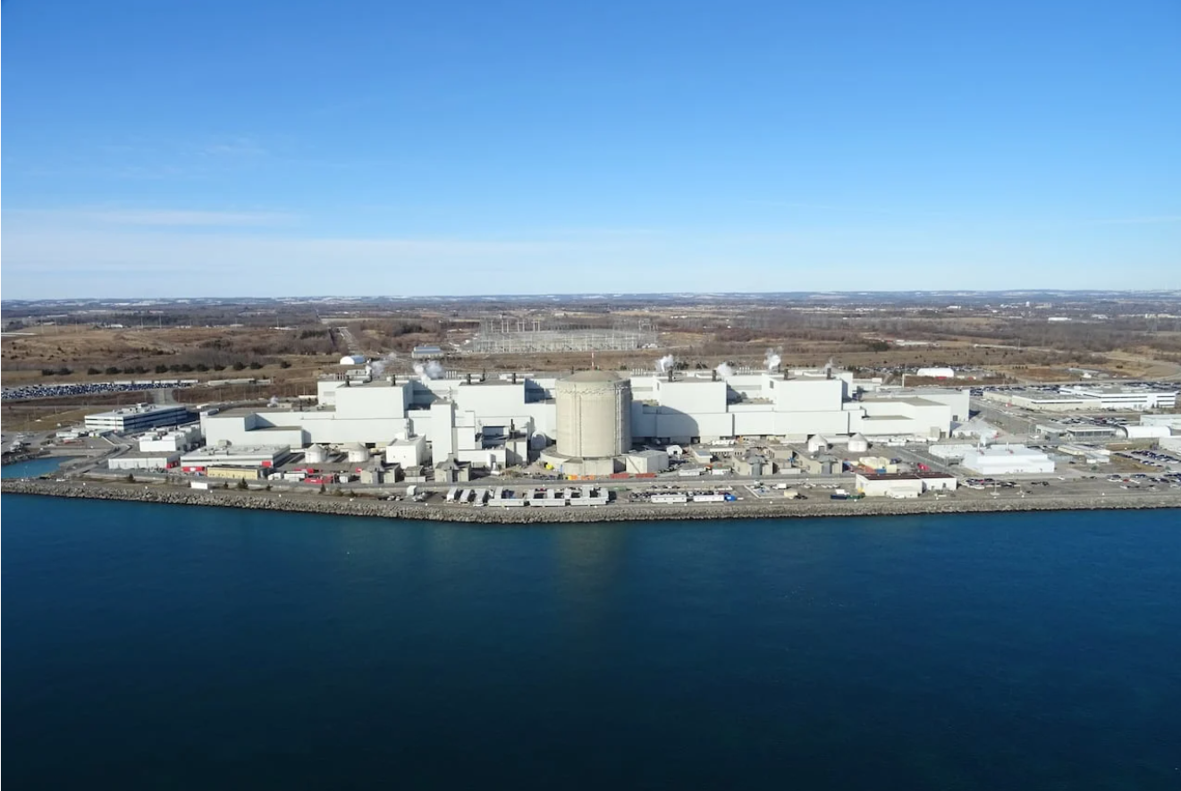 Aerial view of a large industrial waterfront facility beside calm blue water and open land
