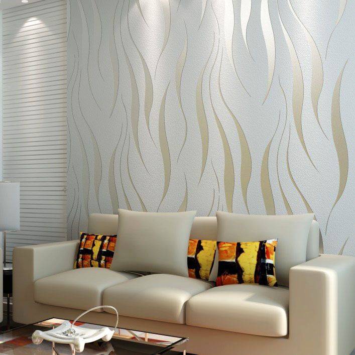 Soggiorno moderno con divano beige, cuscini a fantasia e parete di fondo con texture ondulata.