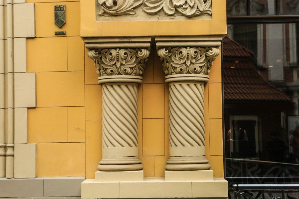 Facciata gialla dell'edificio con colonne in pietra ornate e finiture decorative.