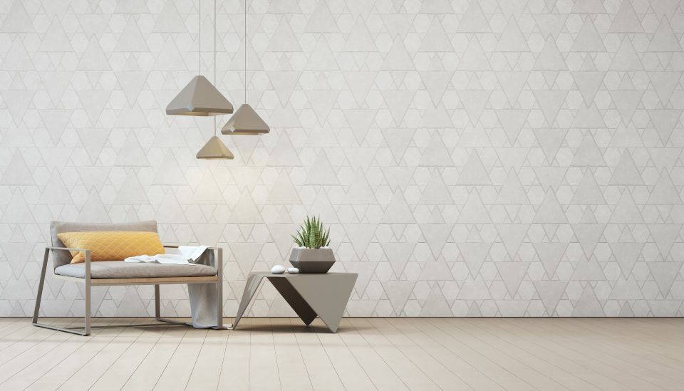 Soggiorno moderno e minimalista con divano grigio, cuscino giallo, applique e tavolino portavaso.