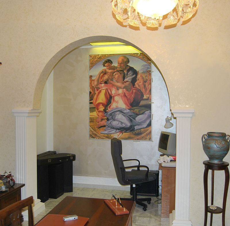Soggiorno con arco, arazzo da parete, sedia da scrivania e urne decorative.