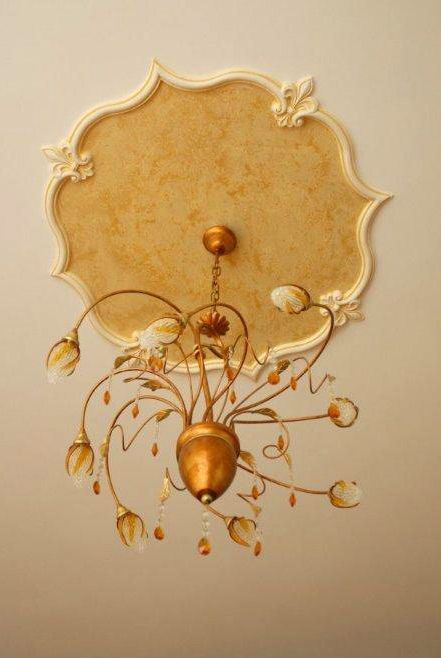 Elegante lampadario dorato con decorazioni floreali su un soffitto beige.