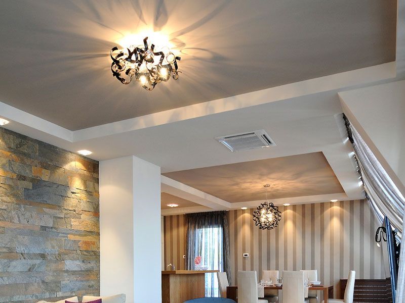 Soggiorno moderno con parete decorativa in pietra, lampadario, carta da parati a righe e ringhiera delle scale.