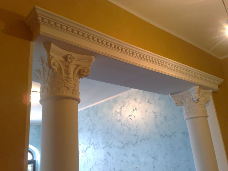 Colonne decorative bianche e modanature ornate incorniciano un angolo di parete e soffitto dalla texture blu.