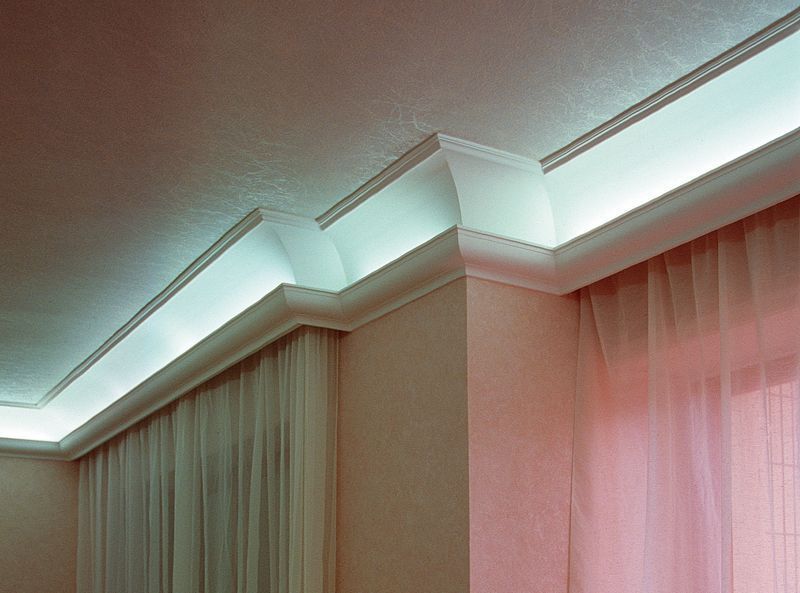 Soffitto con modanature e faretti a incasso sopra tende beige e rosa