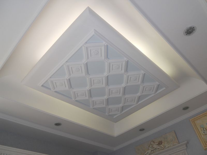 Soffitto a cassettoni decorativo bianco con modanature geometriche e illuminazione indiretta soffusa.