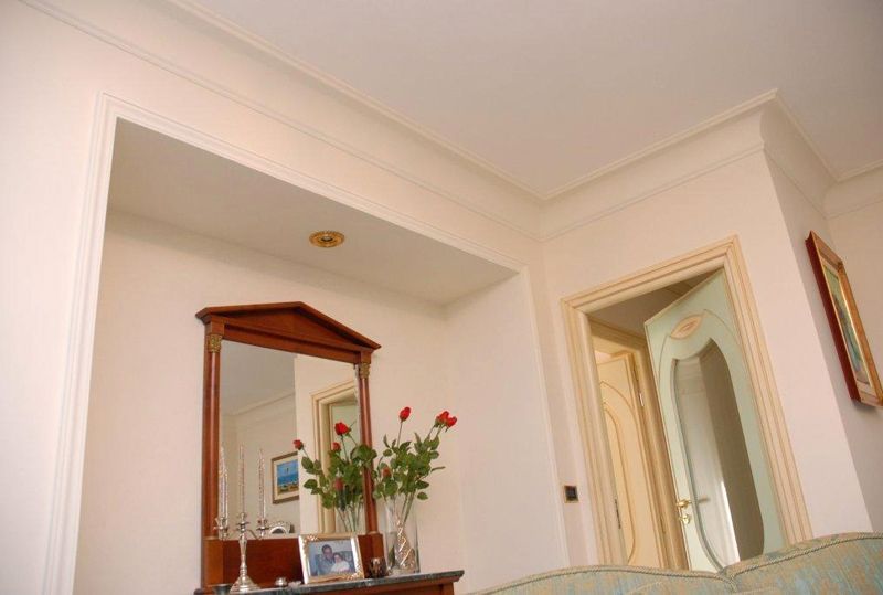 Camera da letto luminosa con specchio sulla toeletta, fiori e porta aperta su un corridoio
