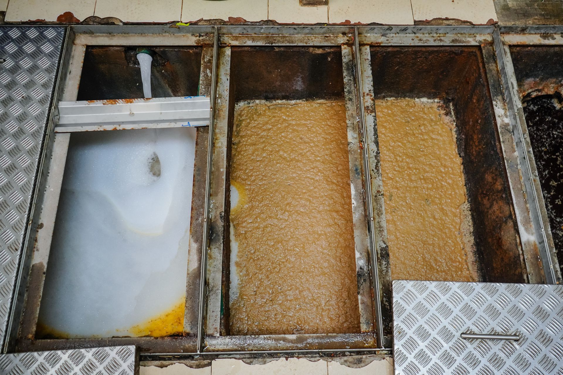 A grease trap in a commercial kitchen awaiting professional grease trap cleaning services.