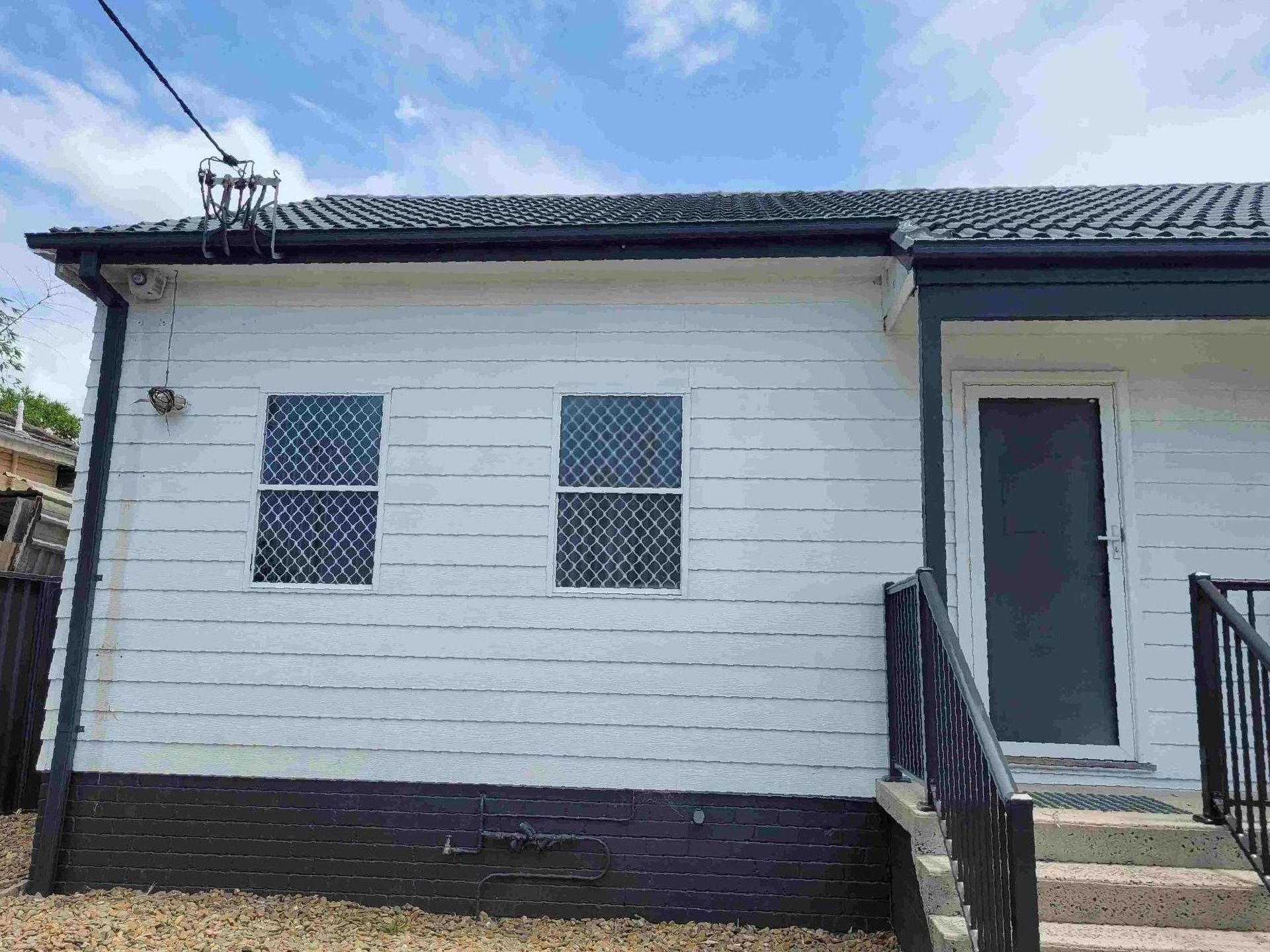 A White house with dark grey roof and gutters — GT Metal Roofing Solutions in Shellharbour, NSW