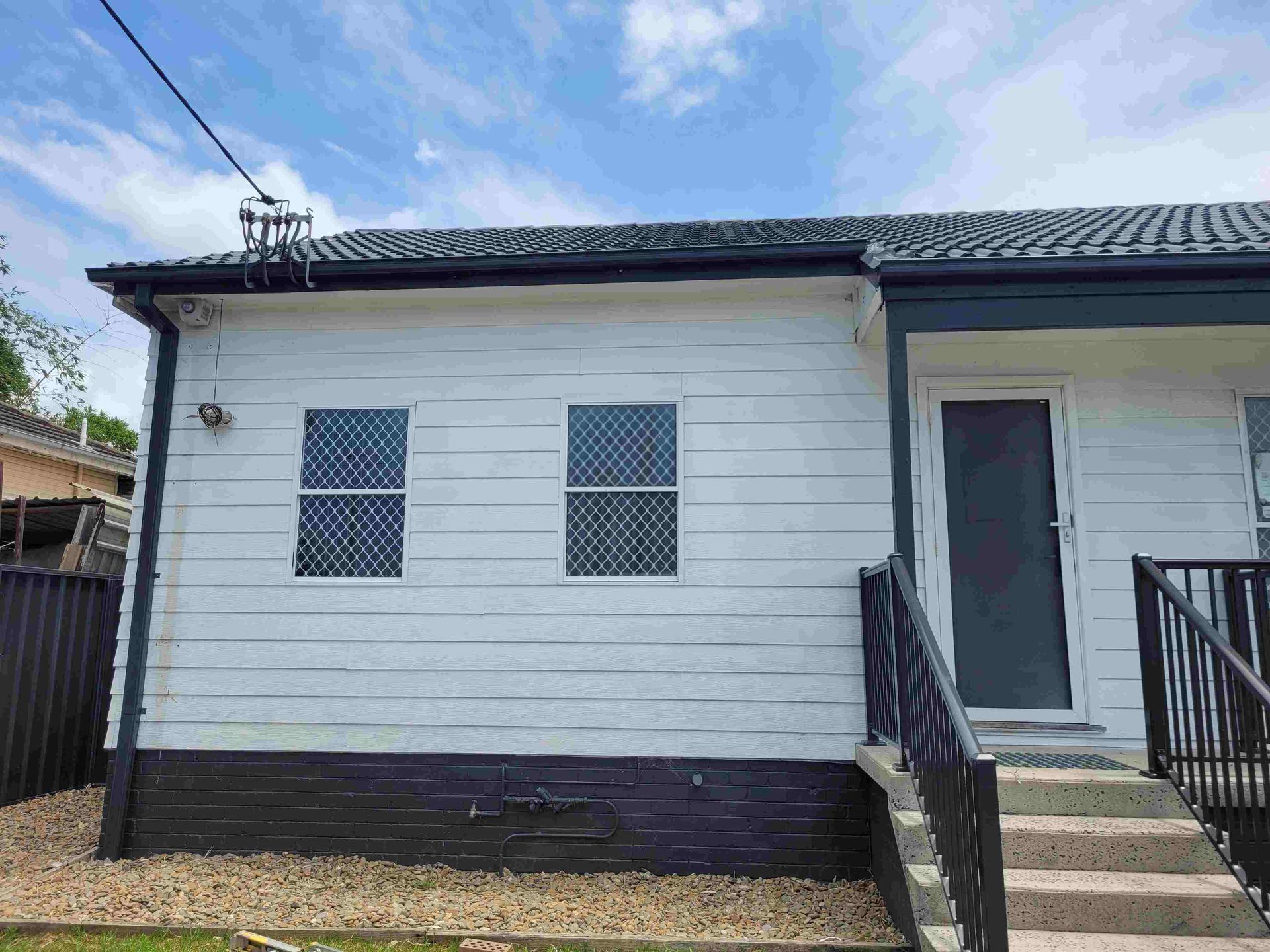 A White House With Stairs Leading Up to the Front Door — GT Metal Roofing Solutions in Corrimal, NSW 