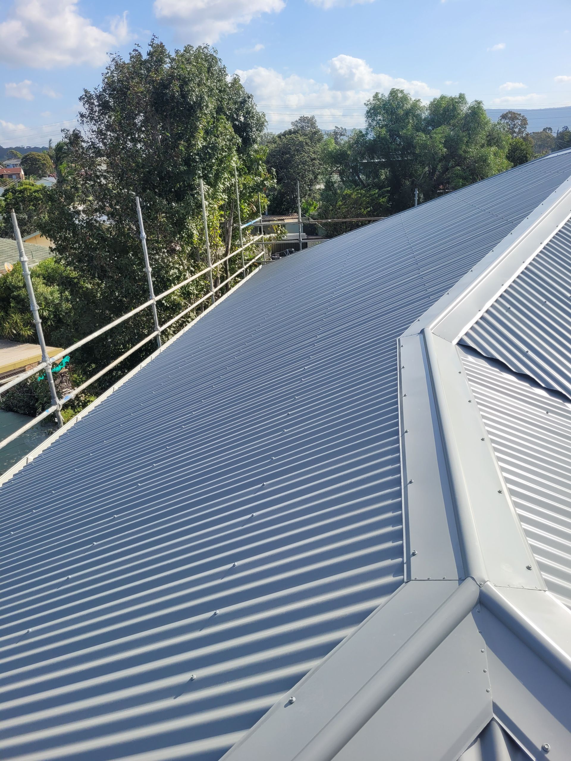 A Close Up of a Roof With Trees in the Background — GT Metal Roofing Solutions in Corrimal, NSW