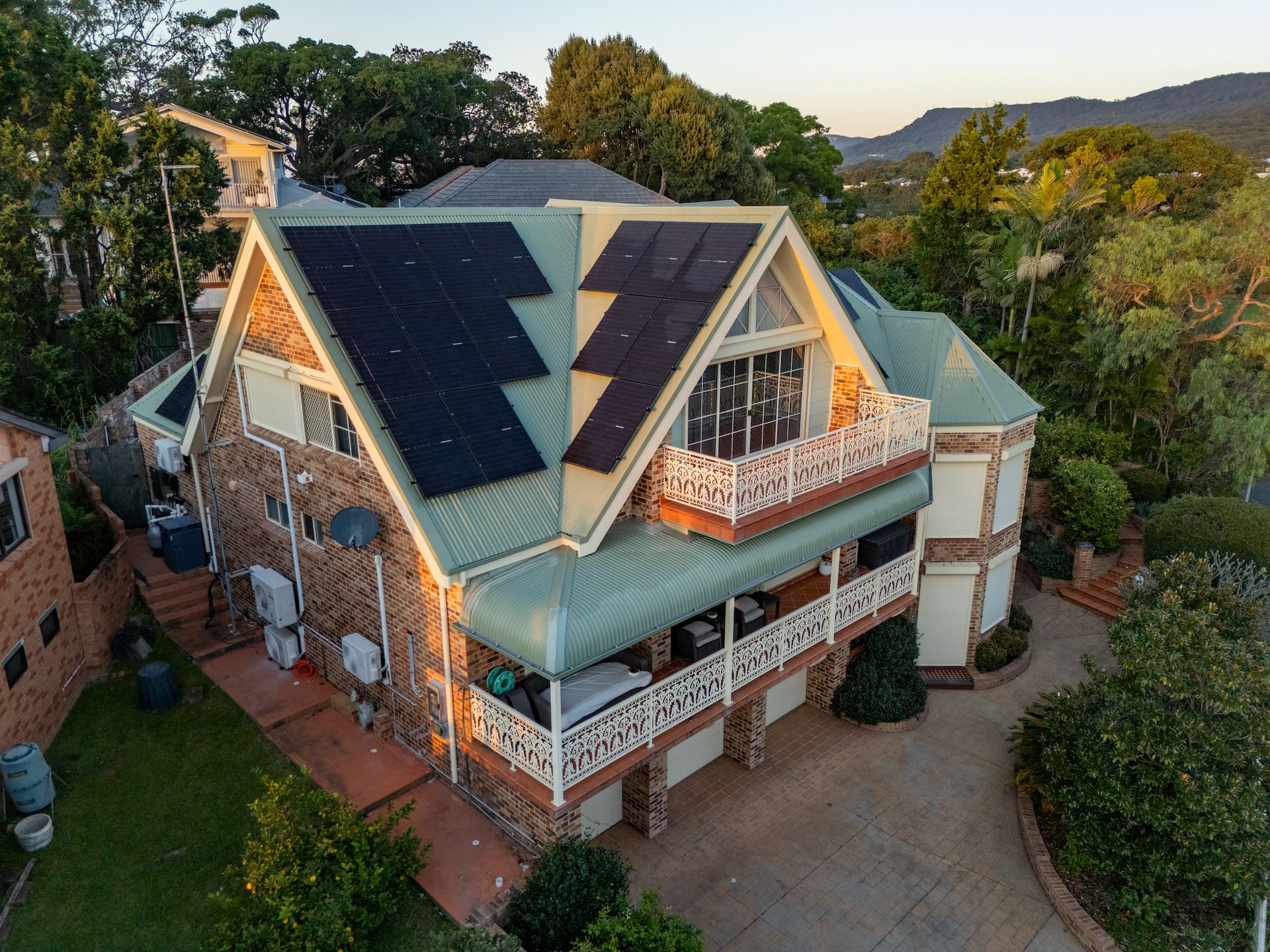 Aerial Shot of a large brick house with green metal roof and many solar panels — GT Metal Roofing Solutions in Corrimal, NSW 